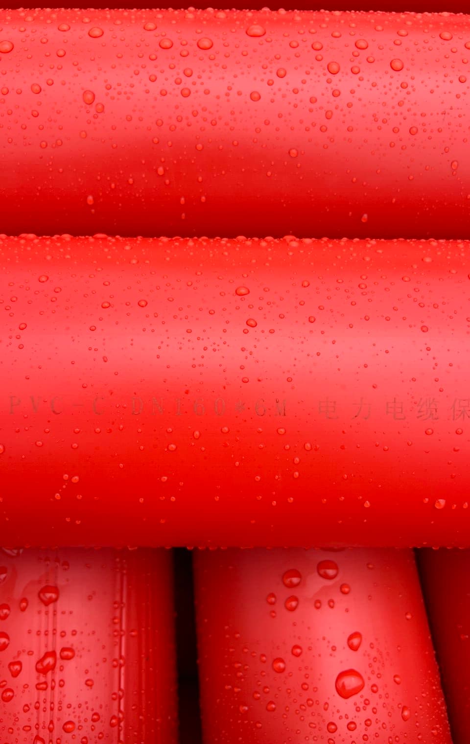 Rotes Kabelschutzrohr in Nahaufnahme, nach dem Regen perlt Wasser auf der Oberfläche