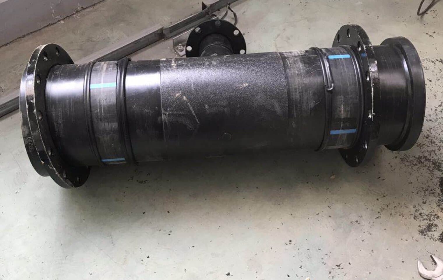 Ein geflanschtes PE-Passstück auf dem Werkstattboden, beidseitig für eine Grubenwasserleitung gebohrt
