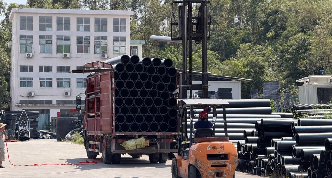 شاحنة مسطّحة تُحمّل بحزم أنابيب HDPE بواسطة رافعة شوكية في منطقة الشحن