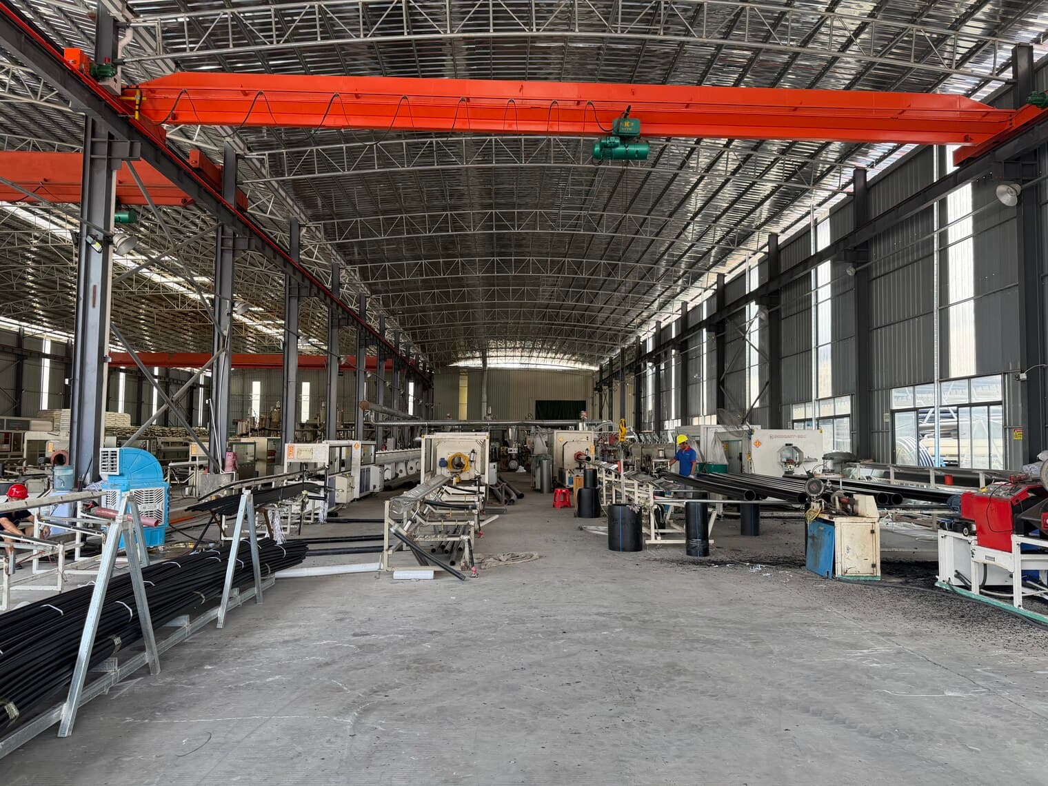 Vue sur toute la longueur du hall de production, au-delà des lignes et postes matière
