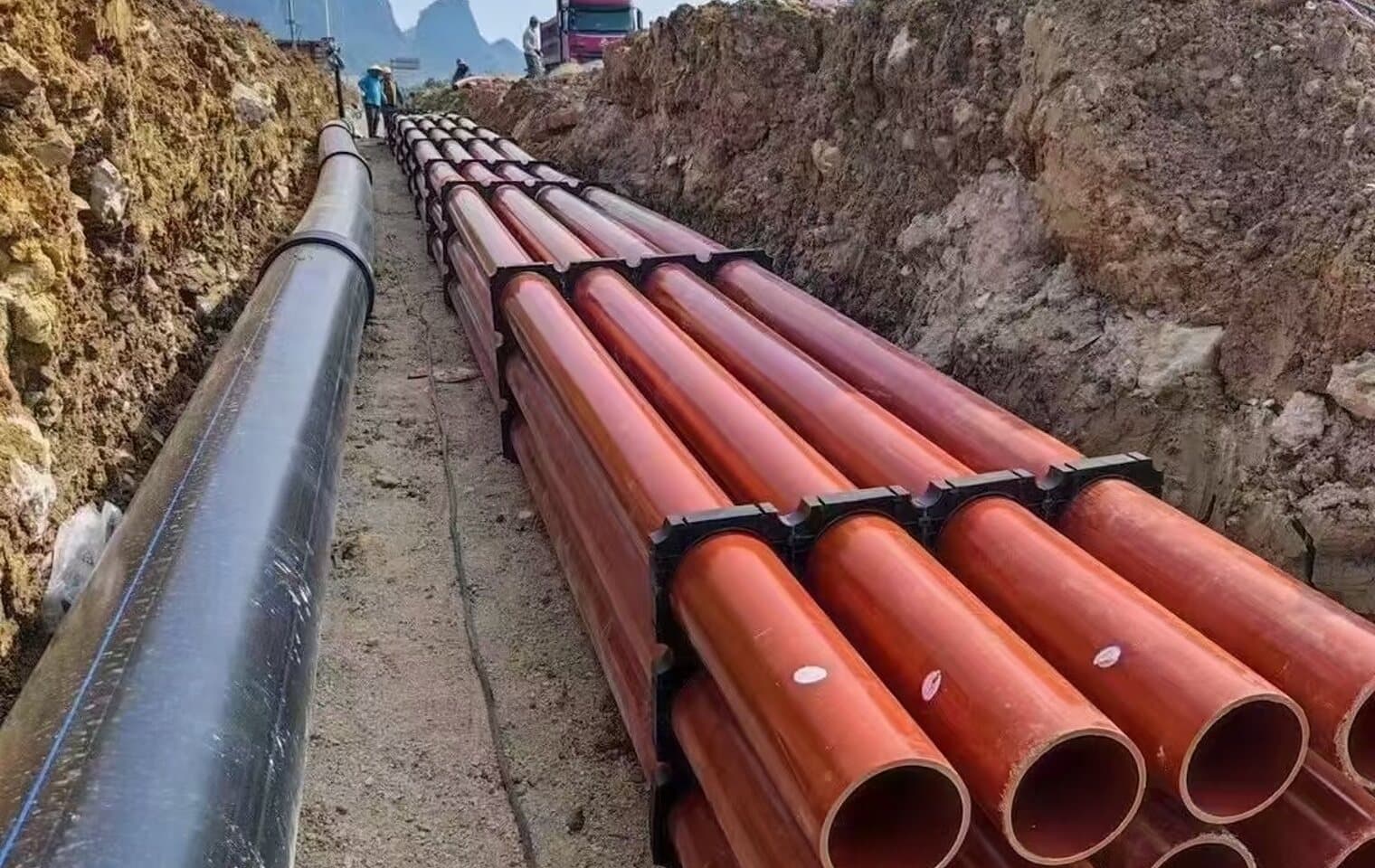 Water main and conduit bundles laid along an open trench on site